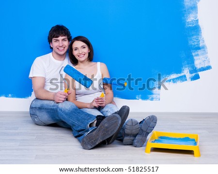 Happy young couple siiting on the floor near the painted wall