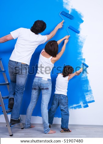 Young family brushing the wall together into the blue color