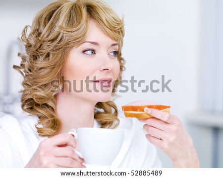 Pretty young woman with beautiful easy smile having breakfast in the kitchen