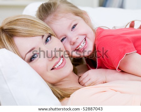 Close-up portrait of happy cheerful beautiful young mother with her little smiling daughter - indoors