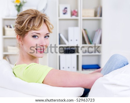 Portrait of happy young beautiful woman sitting on the sofa