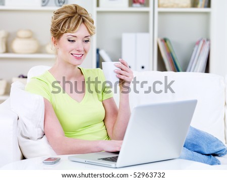 Young woman in casuals with cup of coffee and laptop in the sofa at home