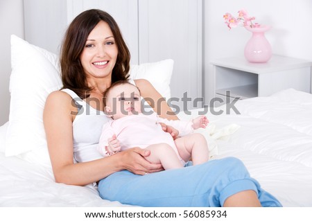 Portrait of beautiful smiling young mother sitting with baby at home