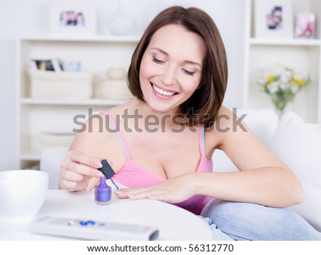 Attractive pretty young woman with happy smile coloring nails on her hands