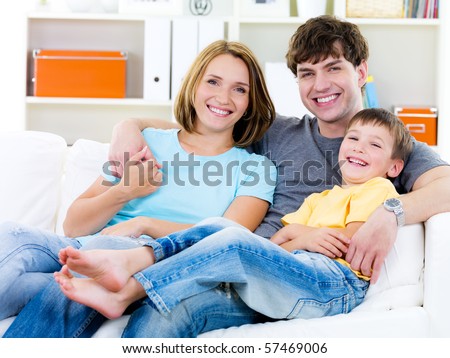Beautiful young happy family with son sitting on the sofa - indoors