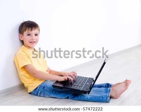 Smiling little child with laptop sitting in empty room - indoors