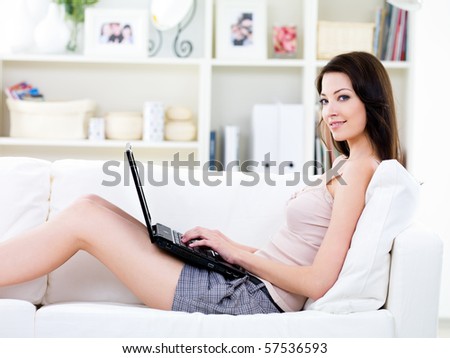 Young woman with beautiful smile relaxing on the sofa and using laptop - indoors