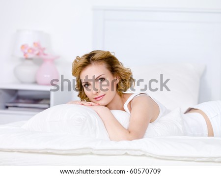 Beautiful young blond woman relaxing on a bed at home