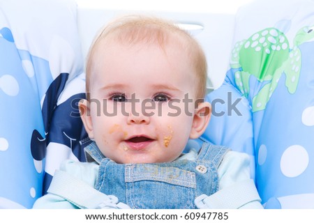 Beautiful happy baby with dirty mouth after cookie - indoors