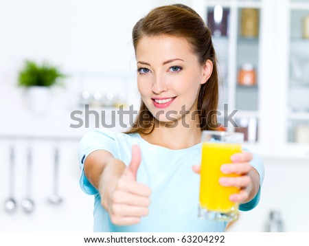 successful young woman thumbs-up with a glass of fresh orange juice