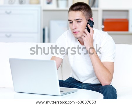 young man speaks on the phone and works on the laptop