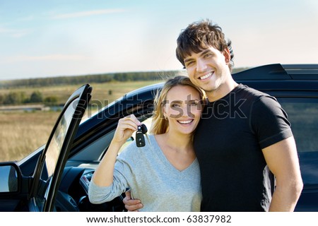 portrait of happy beautiful couple showingh the keys standing near the car