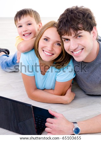 Portrait of happy laughing young family with little son and with laptop - indoors