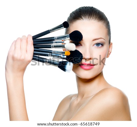 Portrait of the beautiful woman with make-up brushes near attractive face. Adult girl posing over white background