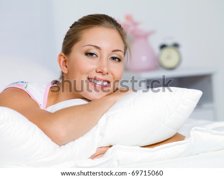 Portrait of the happy young woman having a rest on a bed at home