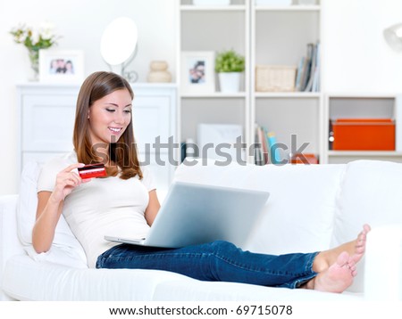 young beautiful woman holding credit card and  looks in the laptop - indoors