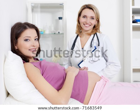 Happy young pregnant woman and her doctor in hospital