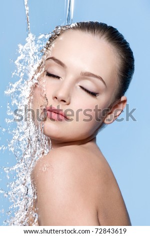 Young sensuality beautiful teen with clean skin with splash of water - blue background
