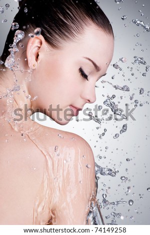 Splashes and drops of water around the female face with clean skin - vertical