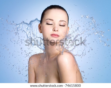 Beautiful portrait of  woman with fresh skin in splashes of water - blue background