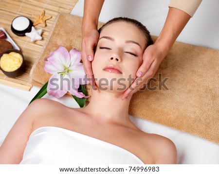 Relaxing beautiful woman having a massage for her skin on a face in beauty salon - horizontal