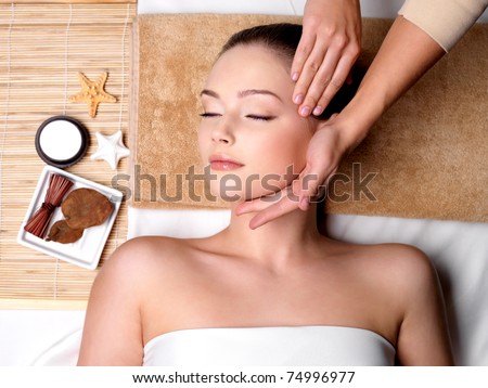 Pampering and massage for beautiful face of young woman in spa salon - indoors