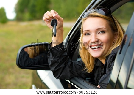 Beautiful young happy woman in  car showing the keys - outdoors