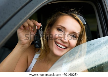 Beautiful young happy woman in the new car with keys - outdoors