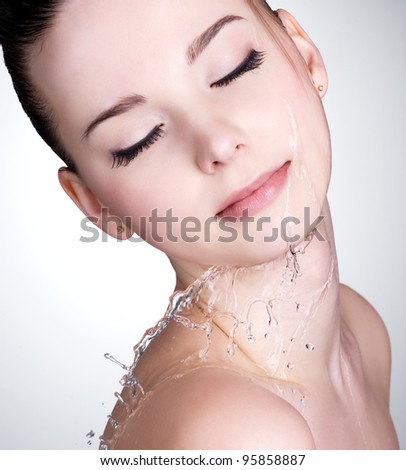 Close-up portrait of young woman with drops of water on her beautiful face