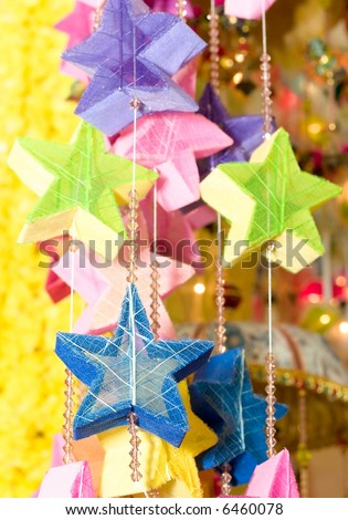 Colorful stars, made from recycled paper and dried leaves, strung with beads creating a mobile sold in a bazaar