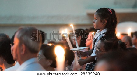 SINGAPORE - APR 10: An unidentified girl sits on her father’s shoulder holding a lighted candle at a Good Friday Mass conducted at St. Joseph’s Church April 10, 2009 in Singapore.