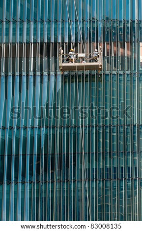 Window Washers  cleaning a complex all-glass facade of a modern building
