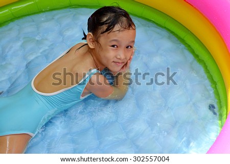 Asian little young girl playing water in small pool