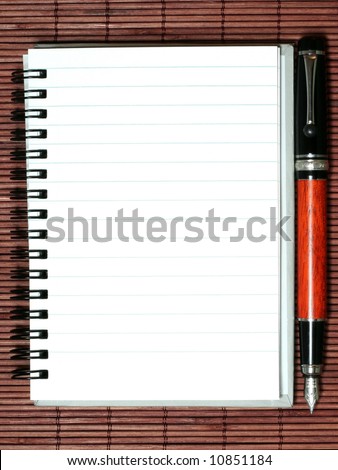 notebook with pen on brown bamboo mat