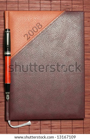 brown diary with pen on bamboo mat