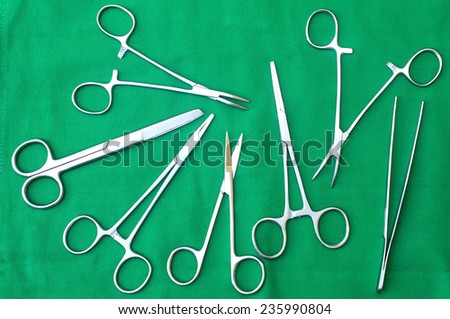 collection of surgical instrument tools on the green surgical drape