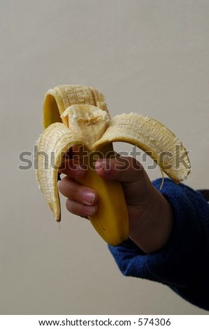 boys hand holding up half eaten banana