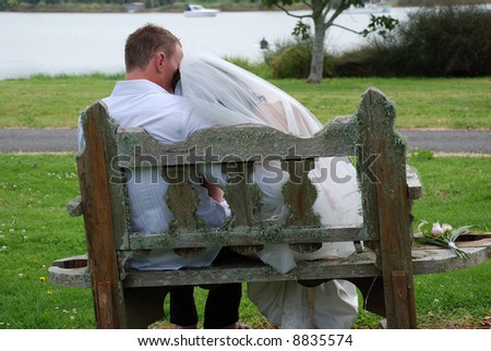 back of bride & groom sitting on wooden seat