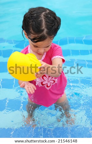 cute toddler girl playing with rubber ducky in swimming pool