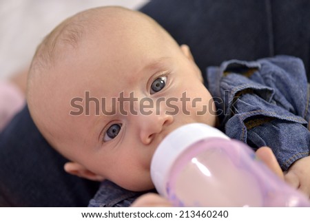 Close-up of a baby girl with beautiful blue eyes bottle feeding