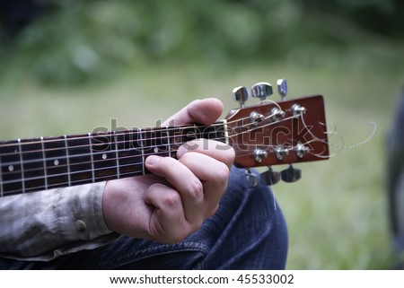 Hand holding a signature stamp of an acoustic guitar close up