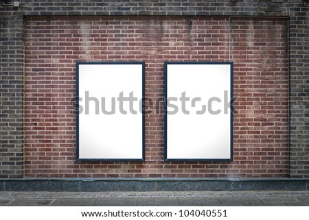 Two blank billboards attached to a buildings exterior brick wall.