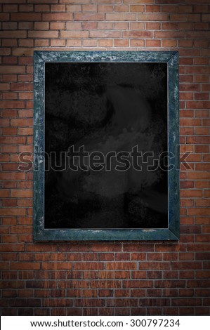 A blank blackboard under a spotlight and hanging on a brick wall.