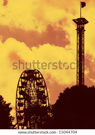 fairground rides silhouetted against a filtered evening sky