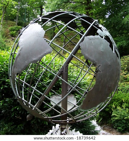 metal sculptured globe of the planet earth in a wooded area