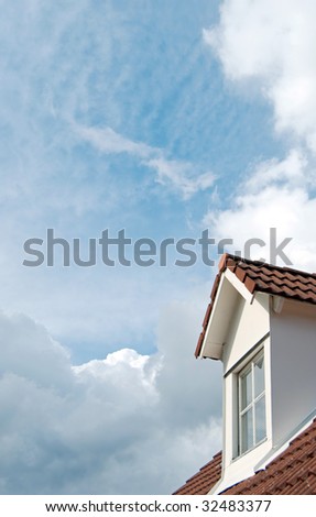 A second floor dormer window situated on a house roof against a heavenly sky background.