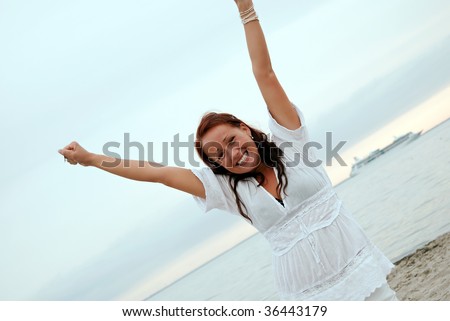 A beautiful, fit and healthy young woman throws her hands in the air in a fit of joy.