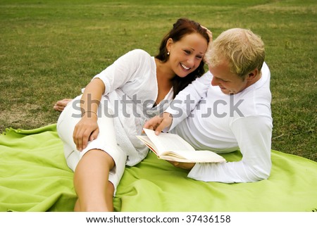 A young man reads poetry to his beautiful partner during a romantic picnic