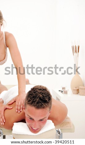 A young man relaxes as he enjoys a luxurious spa treatment from a female masseuse.