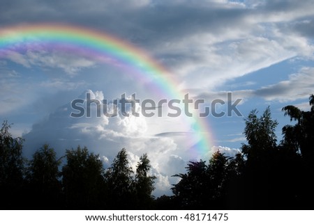 A rainbow set against a beautiful darkened cloudscape to indicate an approaching storm.